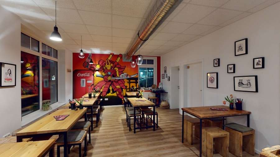 Suchmaschinenoptimierung Hannover - Ein kleines Restaurant mit Holztischen und -stühlen zeigt ein farbenfrohes Roboter-Wandbild an der Rückwand und gerahmte Kunstwerke an den anderen Wänden. Mit heller Beleuchtung, einem glatten Holzboden und einem Coca-Cola-Automaten in der hinteren Ecke gewinnt dieser Ort schnell an Aufmerksamkeit und erreicht ein hohes Ranking bei Google. Local SEO Agentur Hannover.
