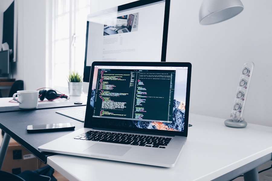 Suchmaschinenoptimierung Hannover - Ein Schreibtisch mit einem Laptop, auf dessen Bildschirm Code angezeigt wird, einem externen Monitor, einer Lampe, einer weißen Tasse und Kopfhörern. Der Schreibtisch steht in der Nähe eines Fensters und vor dem Monitor steht eine kleine Pflanze. Das Setup scheint für einen Programmierer oder Entwickler zu sein, der an der Erstellung einer Webvisitenkarte arbeitet. Local SEO Agentur Hannover.