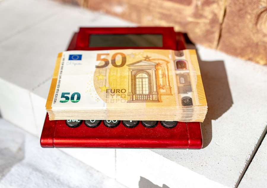 SEO Hannover - Ein Stapel Fünfzig-Euro-Scheine liegt auf einem roten Rechner, der auf einer weißen Oberfläche ruht. Im Hintergrund ist ein Teil einer Ziegelwand zu sehen, der die Kosten für die Website-Erstellung andeutet, die darauf warten, berechnet zu werden. Local SEO Agentur Hannover.