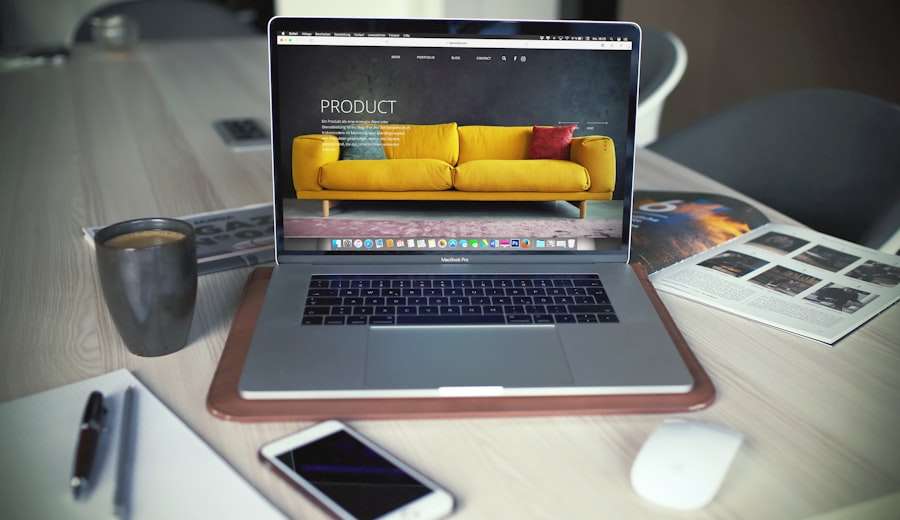 SEO Hannover - Ein Laptop auf einem Holzschreibtisch zeigt ein Webdesign aus Hannover mit einem gelben Sofa. Daneben stehen eine schwarze Tasse, ein Smartphone, eine Zeitschrift und eine Maus auf einem Pad. Der Schreibtisch ist hell und verkörpert einen modernen Arbeitsplatz. Local SEO Agentur Hannover.