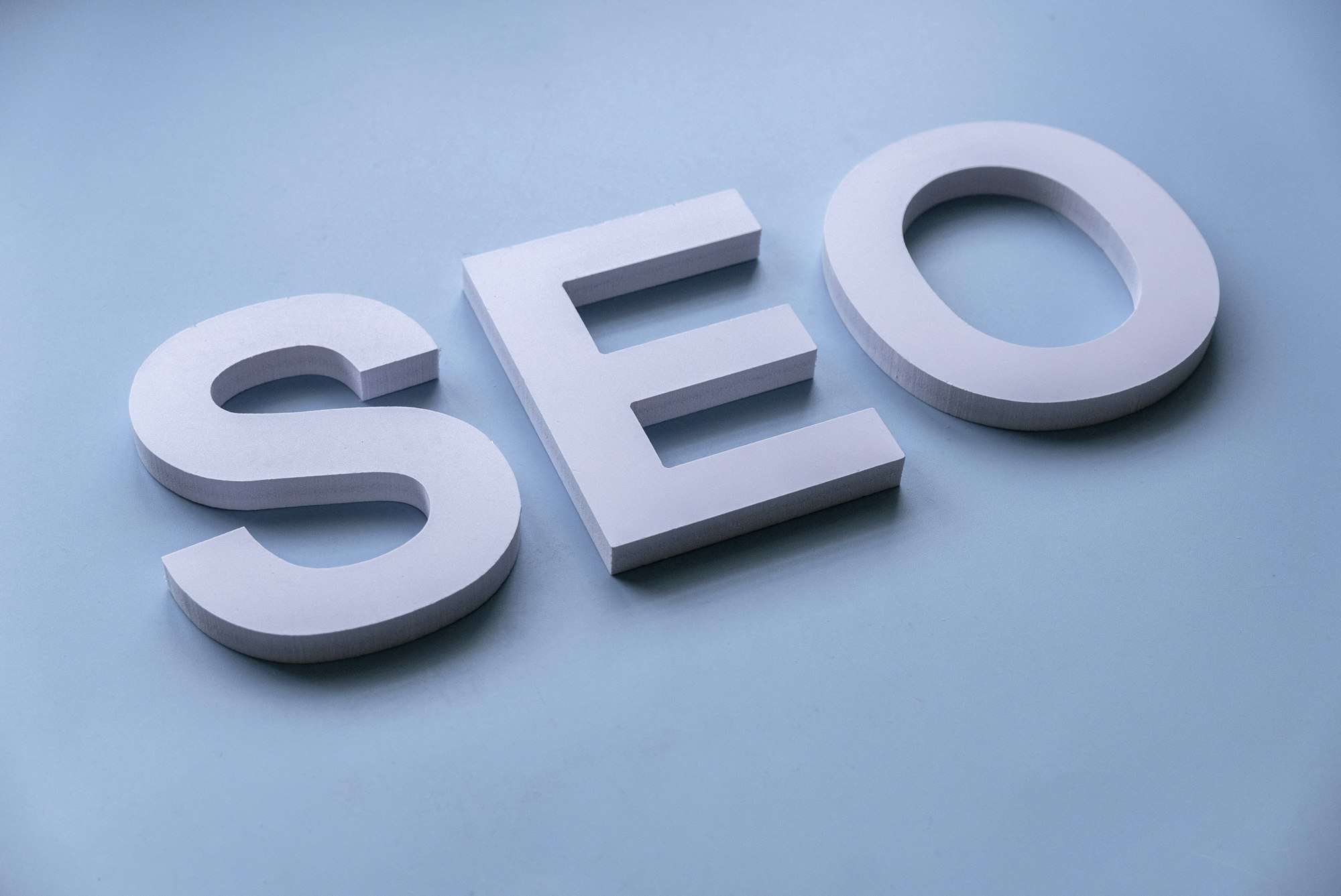 SEO Hannover - Auf hellblauem Hintergrund sind weiße Blockbuchstaben mit der Schreibweise „SEO“ angeordnet. Local SEO Agentur Hannover.