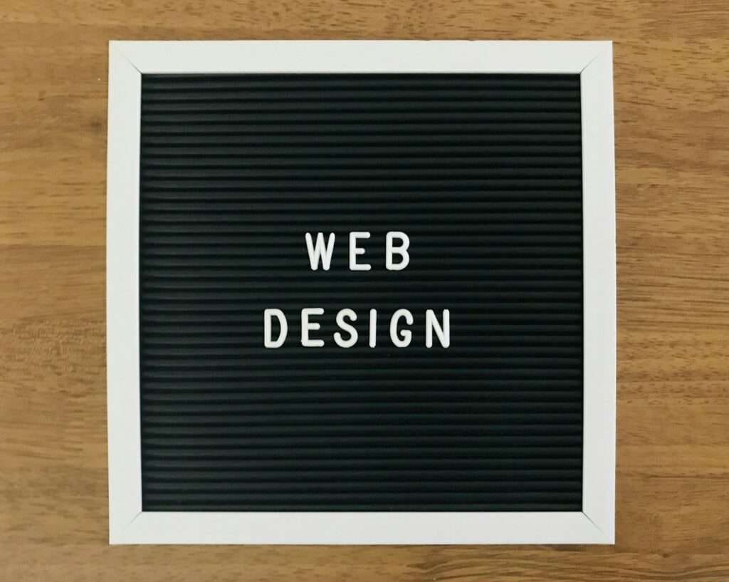 SEO Hannover - Eine schwarze Buchstabentafel mit weißen Plastikbuchstaben, die „WEB DESIGN“ buchstabieren, steht zentriert auf einer Holzoberfläche. Die Tafel, weiß eingerahmt, steht als Leuchtfeuer für Innovation und Kreativität – ähnlich wie ein gut gestalteter Spamfilter unerwünschte Ablenkungen fernhält. Local SEO Agentur Hannover.