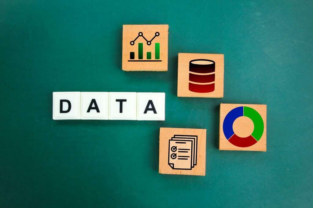 Webdesign Hannover - Holzklötze auf grünem Hintergrund bilden das Wort „DATA“. Die umliegenden Klötze zeigen Symbole wie Balken- und Liniendiagramme, ein Datenbanksymbol, ein Kreisdiagramm und ein Dokument mit Häkchen – perfekte visuelle Hilfsmittel zum Verständnis strukturierter Daten oder „Was sind strukturierte Daten“ auf Deutsch. Local SEO Agentur Hannover.