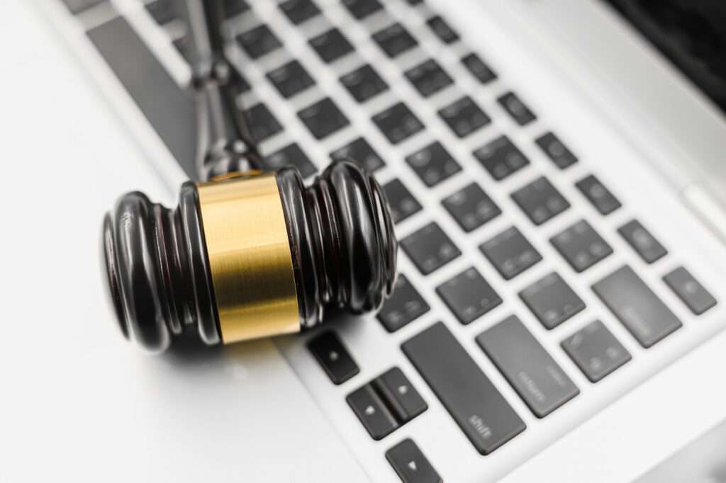 Webdesign Hannover - Ein Richterhammer auf einer Laptoptastatur symbolisiert die Schnittstelle zwischen Recht und Technologie und wirft die Frage auf: Was ist Pflicht bei einer Website? Der Holzgriff und das goldene Band des Hammers liegen diagonal über den schwarzen Tasten der Tastatur. Local SEO Agentur Hannover.