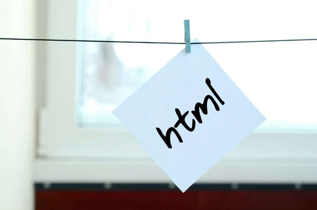 Webdesign Hannover - Ein Stück Papier mit der Aufschrift „html“ ist mit einer Wäscheklammer an einer Schnur befestigt und wirft die Frage auf: „Was ist eine HTML-Sitemap?“ Im Hintergrund ist ein verschwommenes Fenster zu sehen, was darauf schließen lässt, dass das Papier im Haus hängt. Local SEO Agentur Hannover.