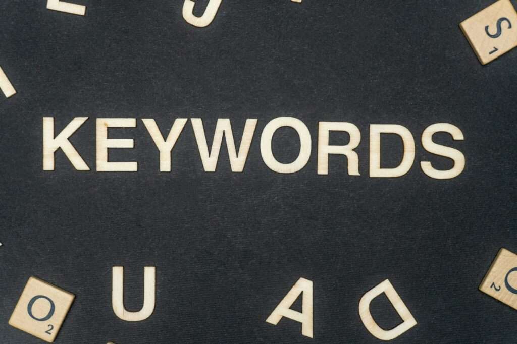 SEO Hannover - Das Bild zeigt den Satz „KEYWORDS“ in großen Holzbuchstaben auf einer schwarzen Oberfläche, umgeben von verstreuten Spielsteinen aus einem Wortspiel. Diese Holzbuchstaben könnten einen zum Nachdenken anregen: „Welche Schlüsselwörter erfassen das Wesentliche der Szene am besten?“ Local SEO Agentur Hannover.
