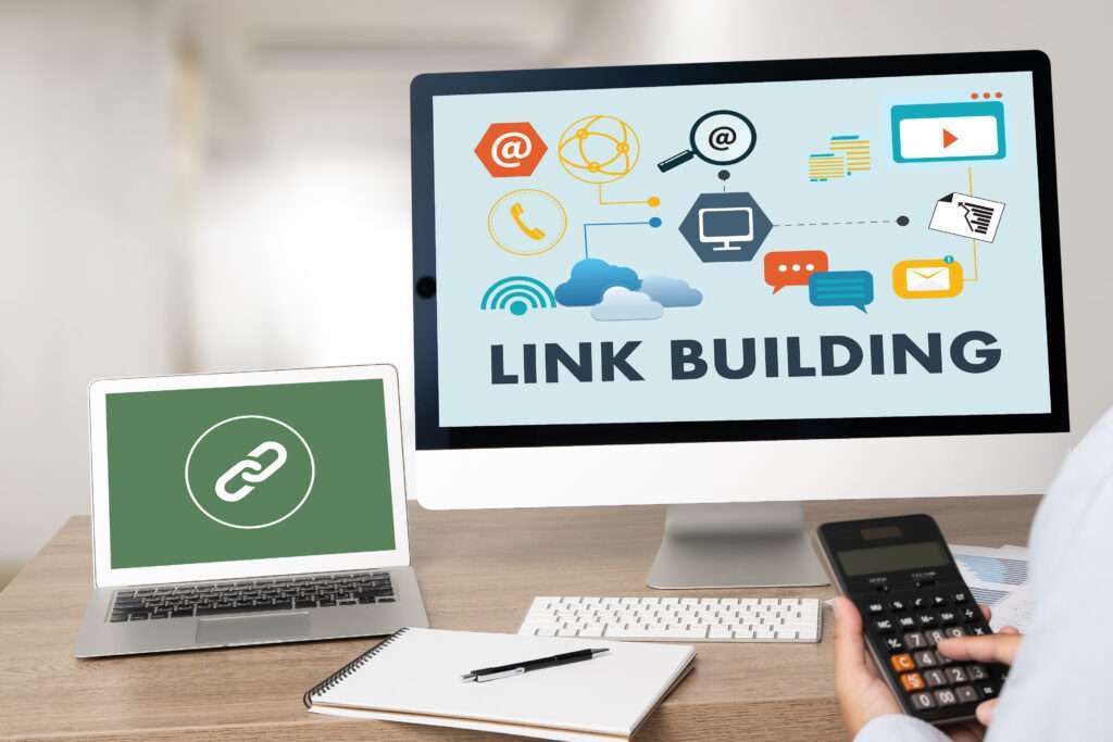 Webdesign Hannover - Eine Person mit einem Taschenrechner sitzt an einem Schreibtisch, auf dessen Bildschirm „Link Building“ und verschiedene digitale Symbole angezeigt werden, und denkt über die Bedeutung der 301-Weiterleitung nach. Auf dem Schreibtisch stehen außerdem ein Laptop mit einem Kettengliedsymbol, ein Notizblock und ein Stift. Local SEO Agentur Hannover.