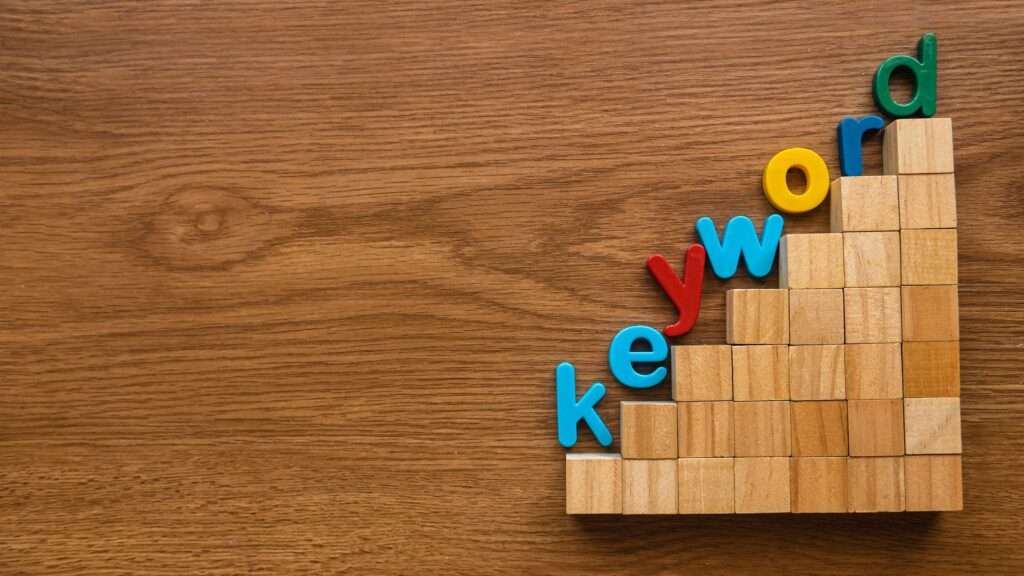 Webdesign Hannover - Auf der rechten Seite einer Holzfläche sind Holzklötze zu einer Treppe gestapelt und entlang der Stufen sind bunte Buchstaben mit dem Wort „Stichwort“ angebracht. Local SEO Agentur Hannover.