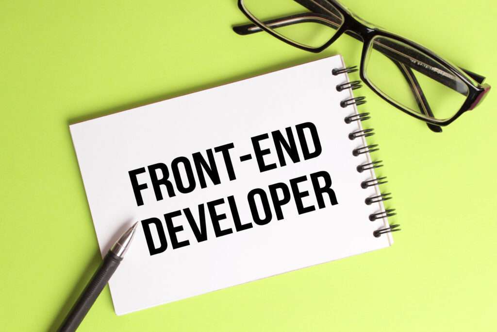 Webdesign Hannover - Ein Notizbuch mit den Worten „Front-End-Entwickler“ in fetten, schwarzen Buchstaben liegt auf einer hellgrünen Oberfläche und verkörpert die Essenz des Frontend-Website-Designs. Neben dem Notizbuch liegen eine schwarze Brille und ein Stift. Local SEO Agentur Hannover.